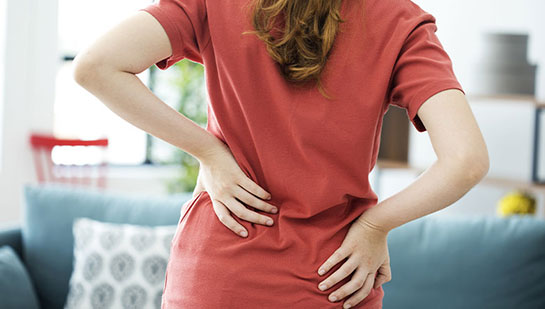 Woman holding lower back in pain before visiting Minnetonka chiropractor