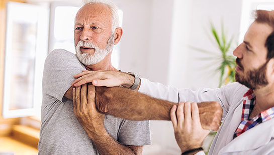 Elderly man receiving shoulder adjustment from Minnetonka chiropractor